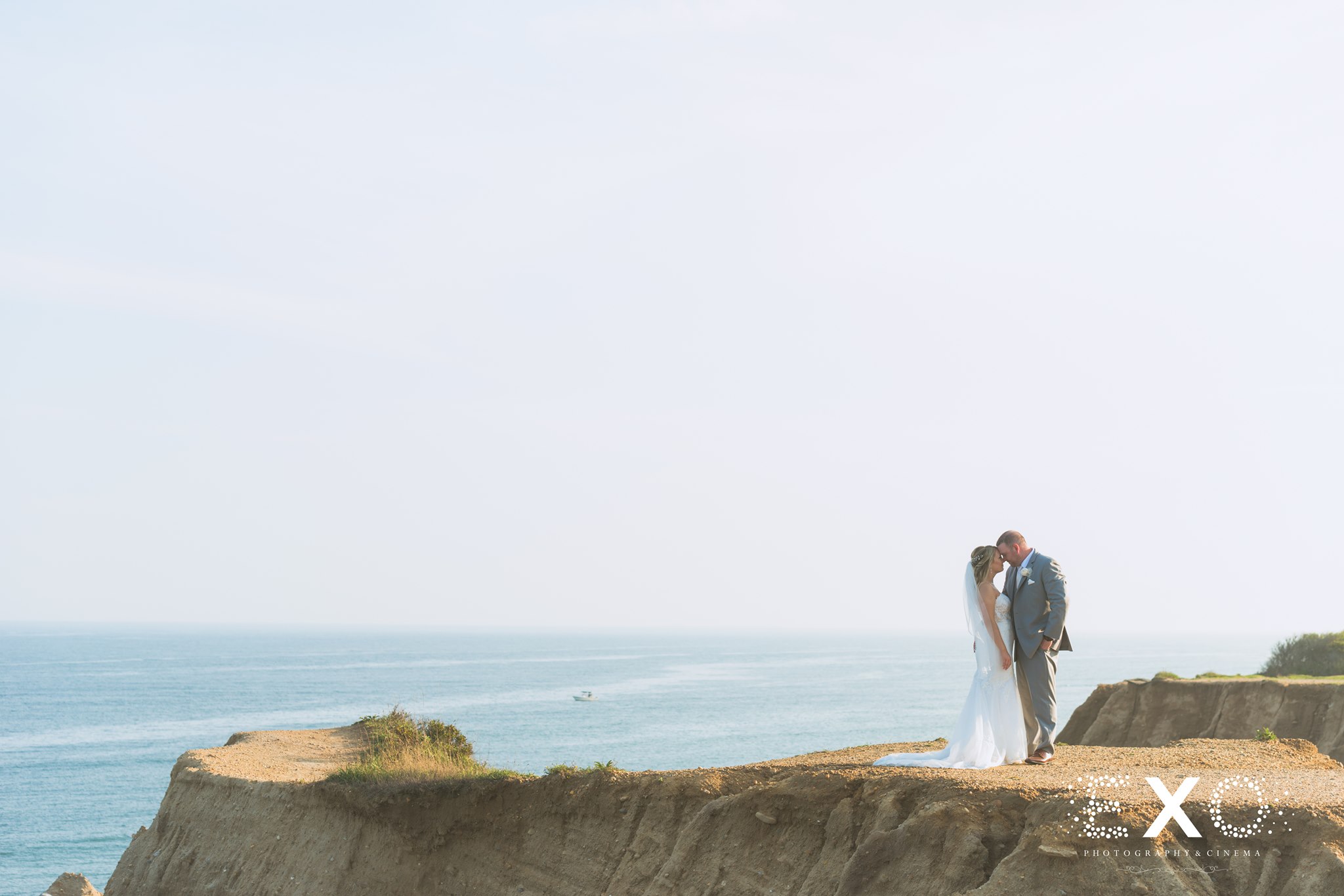 bride and groom holding one another on a cliff at 360 East