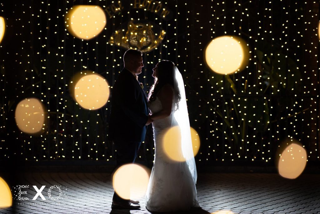 bride and groom standing within the lights at Fox Hollow