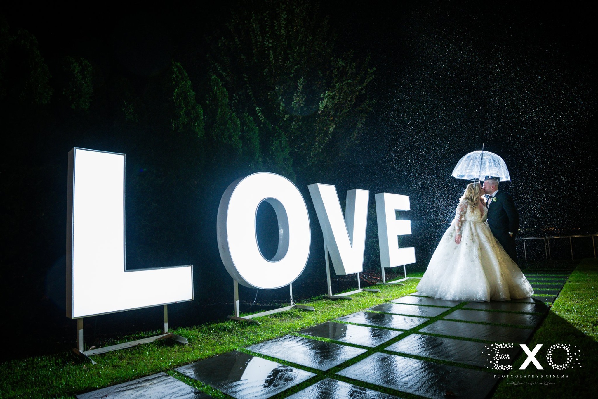 bride and groom in front of love sign