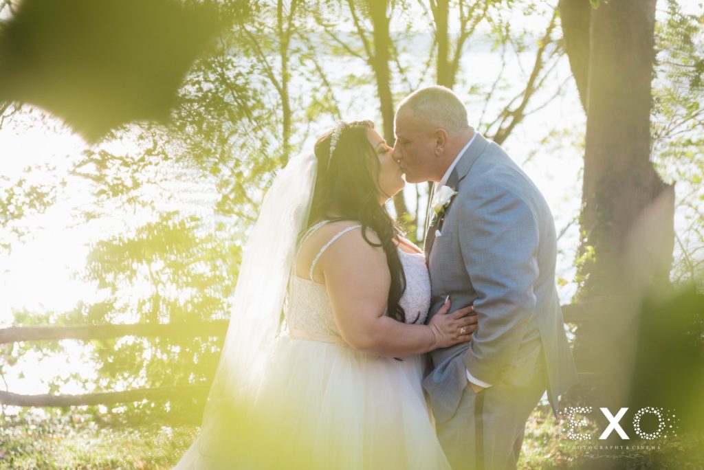 bride and groom kiss with sun shining