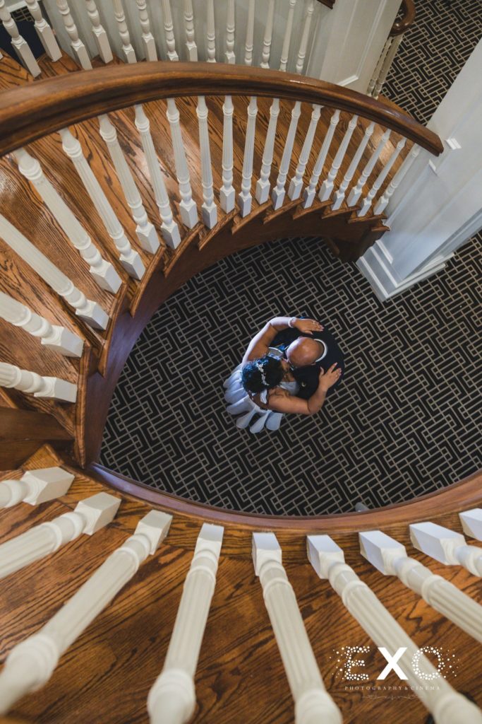 bride and groom kissing under staircase
