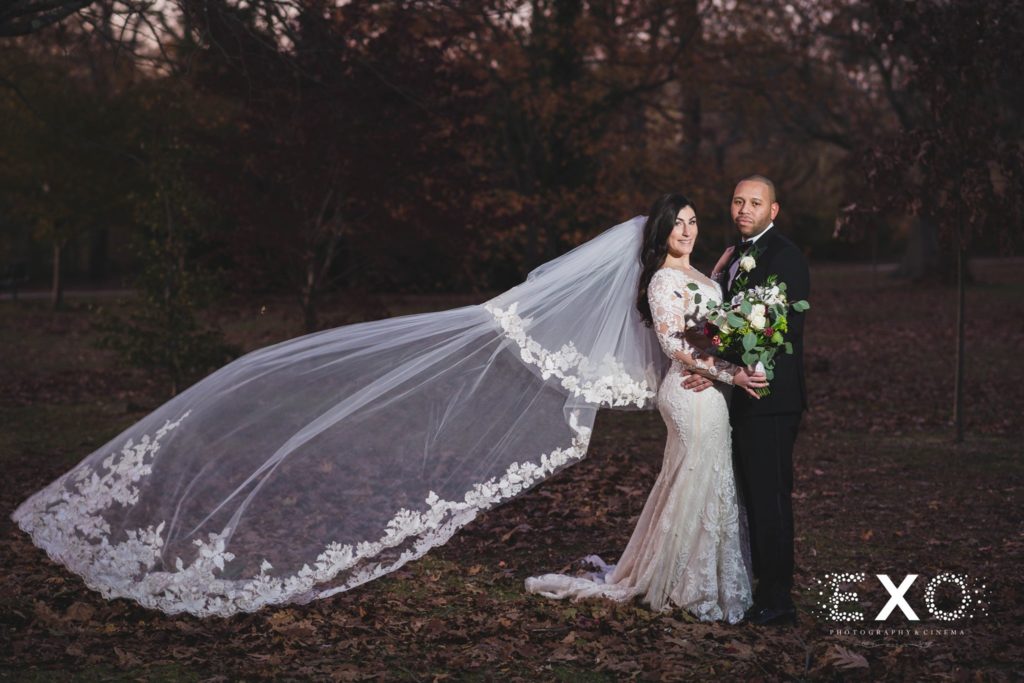 bride and groom with veil blowing in wind