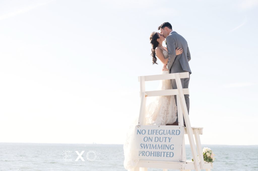 bride and groom kissing on the lifeguard stand
