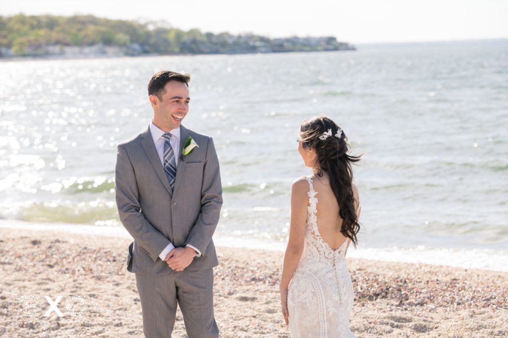 bride and groom smiling at each other on the beach