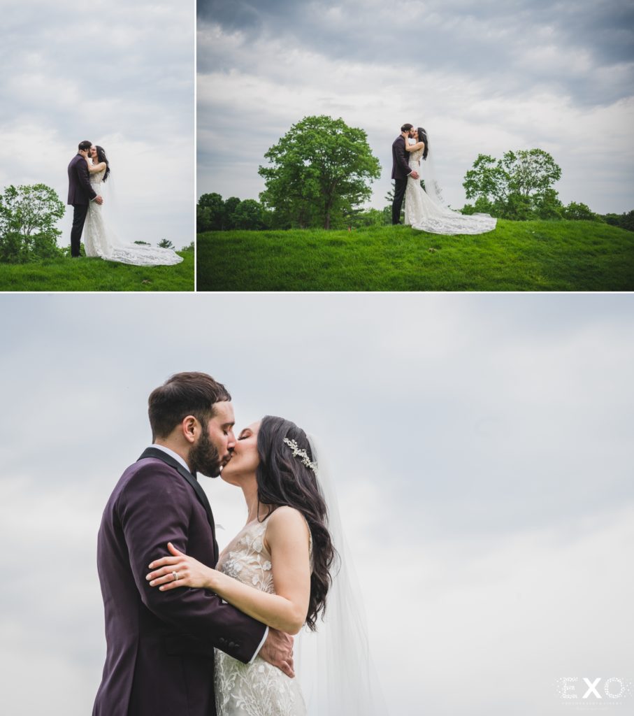 Bride and groom outside kissing on grass.