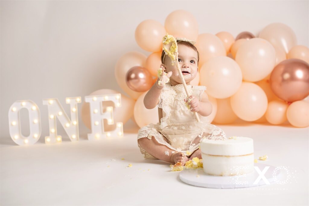 Baby girl holding a big wooden spoon with cake