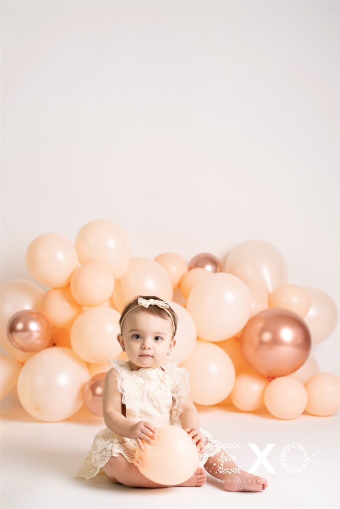 First birthday photos with a baby girl holding a balloon. 