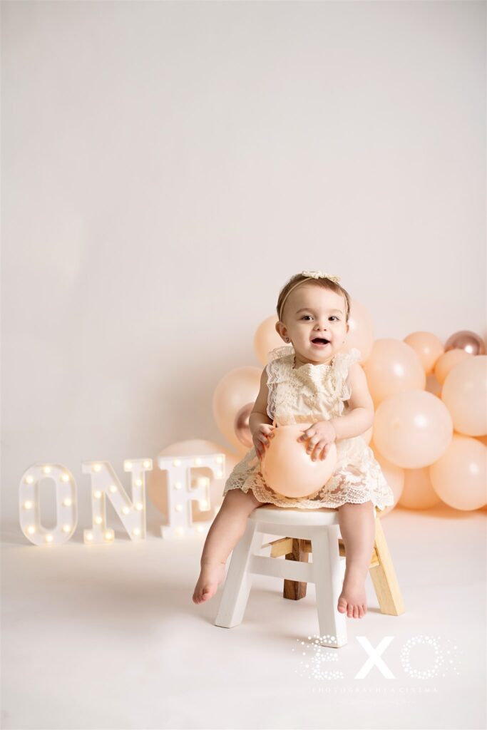 Baby girl sitting on a chair holding a balloon 
