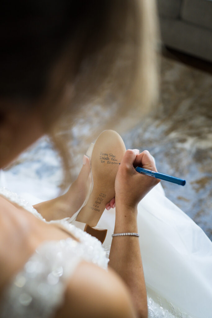 bride writing a message on the bottom of her shoes