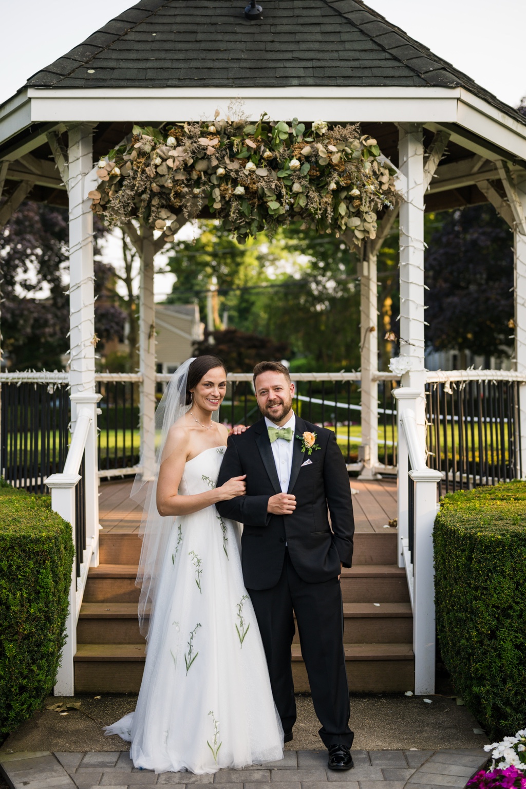 Wedding couple in front of white garden gazebo