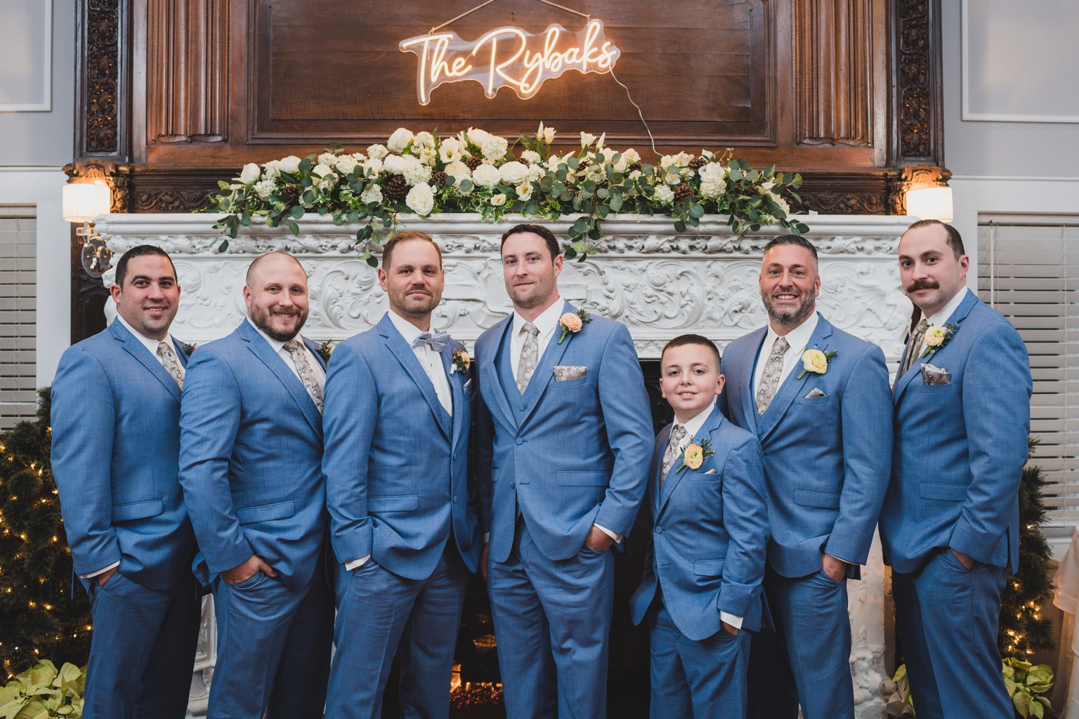 Groomsmen in blue suits by the fireplace at Stewart Manor Country Club