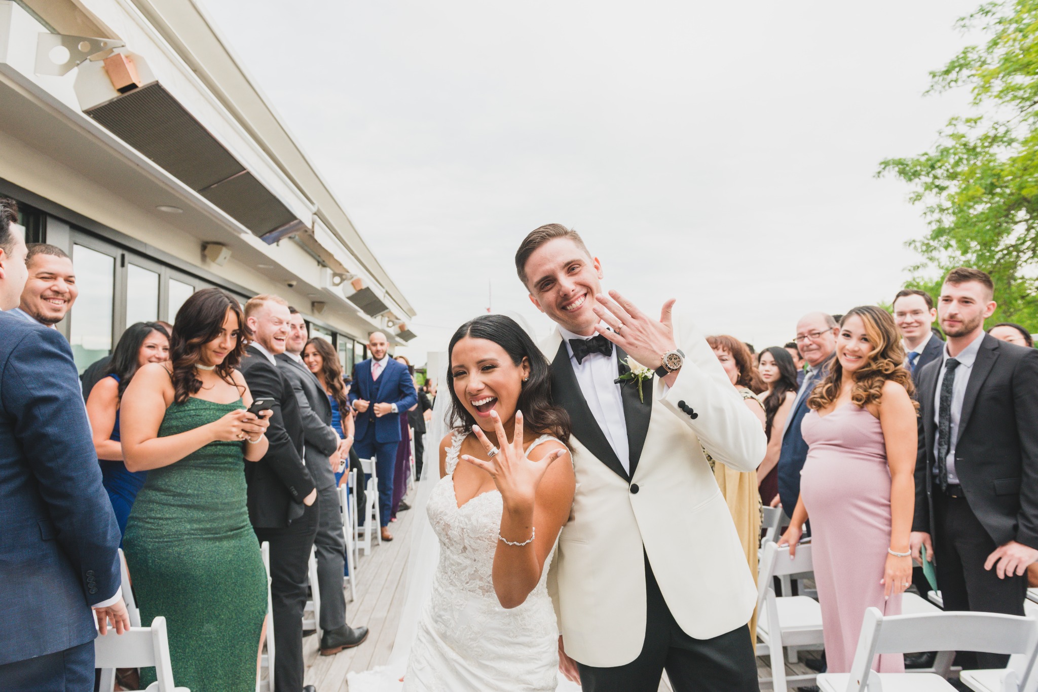 Newly married couple smiling with guests after an outdoor wedding ceremony
