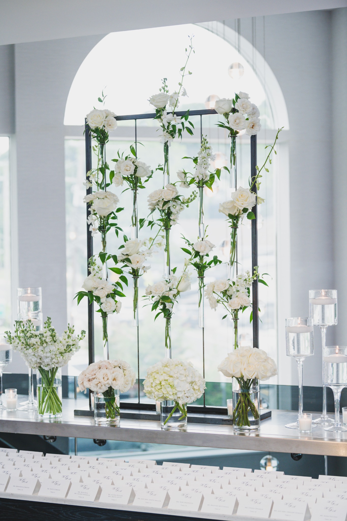 White wedding flowers, floating candles and escort cards at a reception display